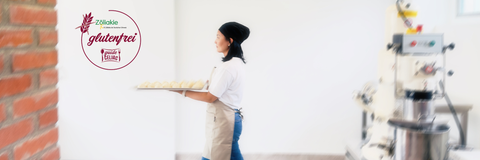 Inhaberin Amy trägt Dumplings auf einem Tablett durch den Raum, außerdem ist das Siegel der IG Zöliakie links abgeildet